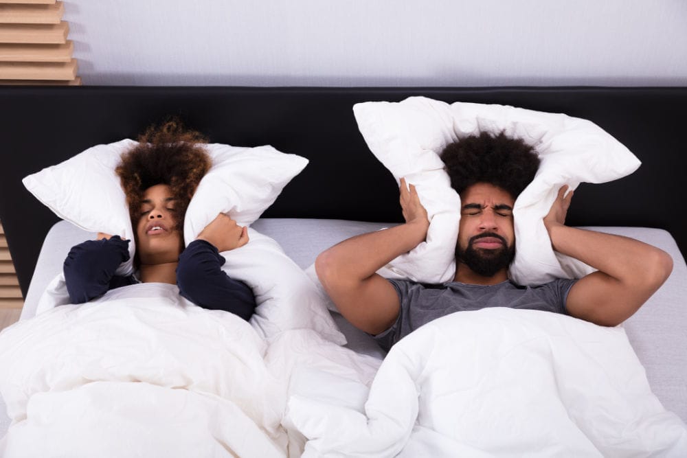 Young Couple in Olympia, WA, Covering Their Ears With Pillows Because The Furnace is Making Noise.