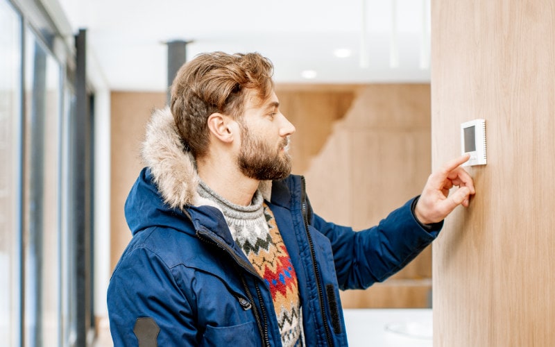 Man in a winter jacket trying to figure out why the thermostat is blank in his Olympia, WA home.