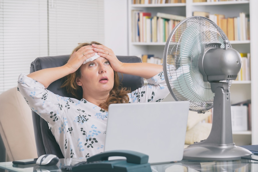 Woman trying to  cool off due to broken air conditioner in home