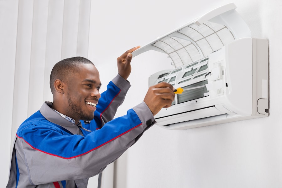 Happy Young African Male Technician Repairing Air Conditioner