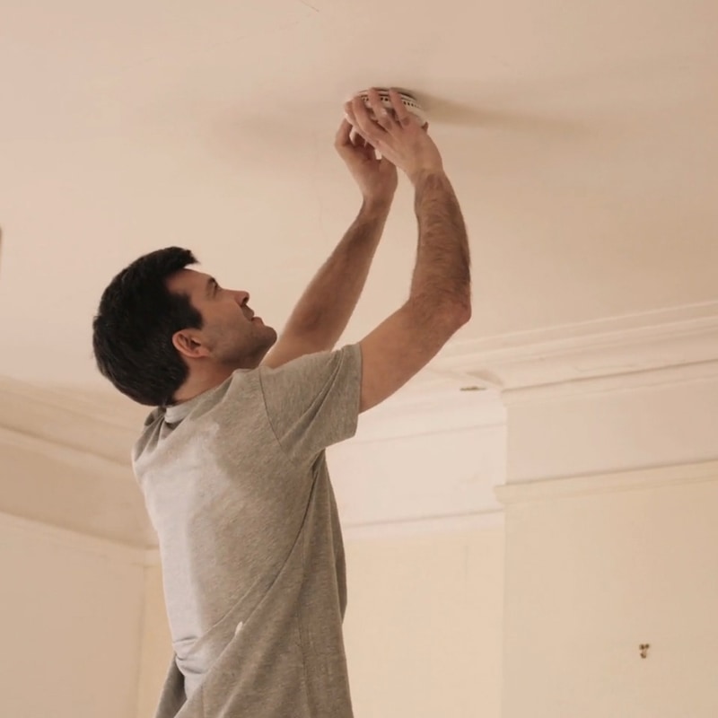 Man changing the batteries in his smoke detector.