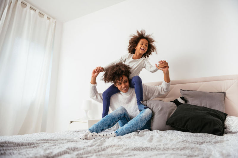 mother and daughter laughing on the bed