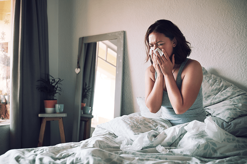 Woman blowing nose inside