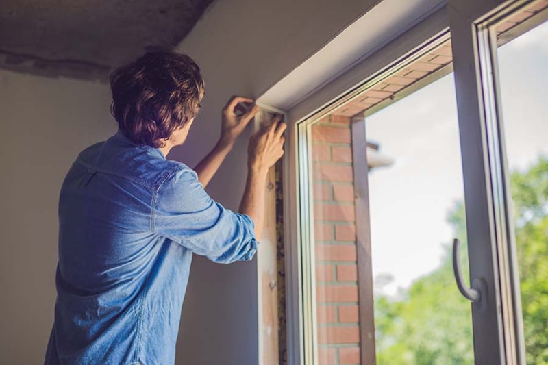 Man in a blue shirt does window installation