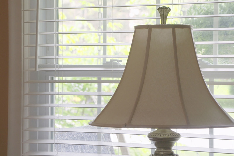 A lamp with open blinds looking outside