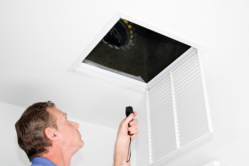 man looking up an air vent