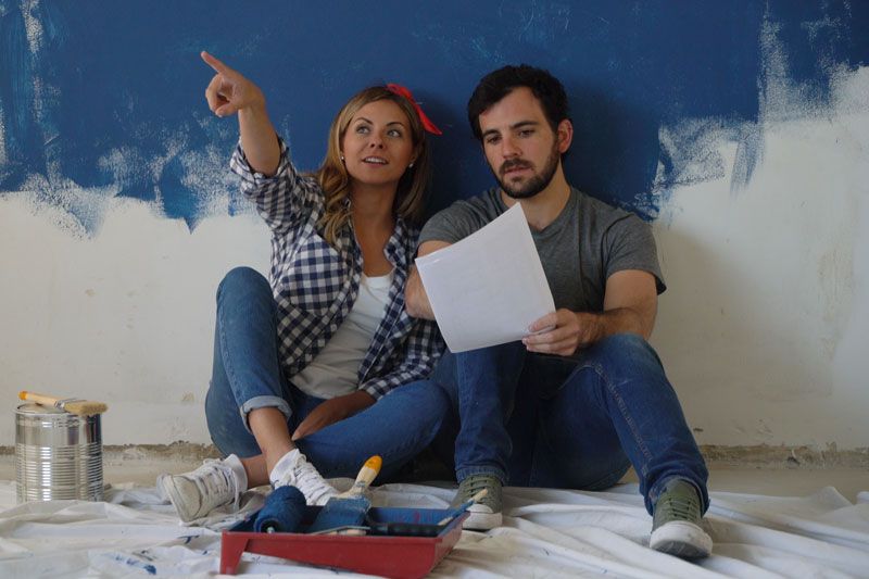 Video - Remodeling Your Home? Don’t Forget Your Comfort! Image shows couple sitting in front of partially painted wall and discussing options for room.