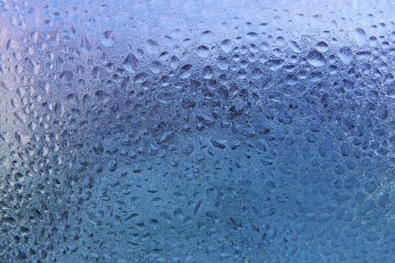 water drops and frost on window glass, close-up natural texture. Controlling Humidity In Your Home.