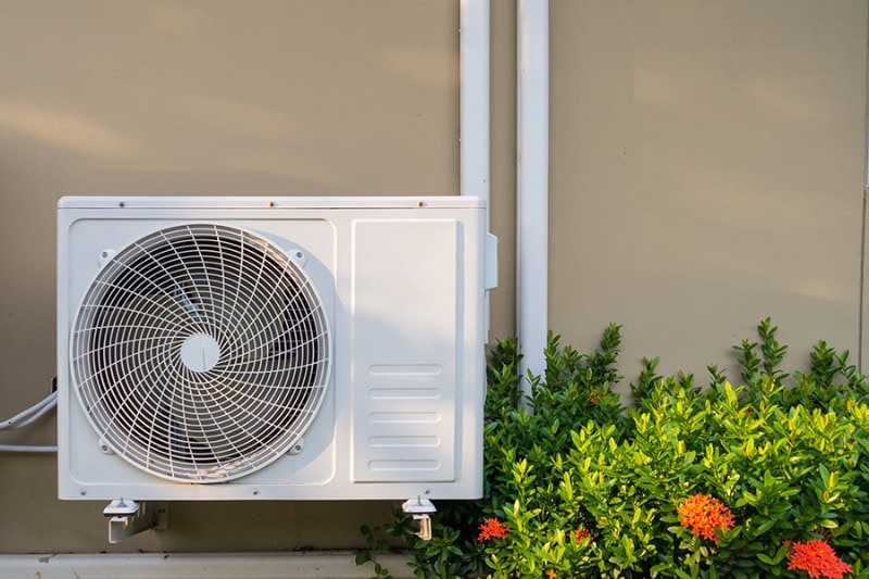 3 Tips to Prevent an AC Breakdown During a Heat Wave. Air conditioning system installation embedded on wall of building.