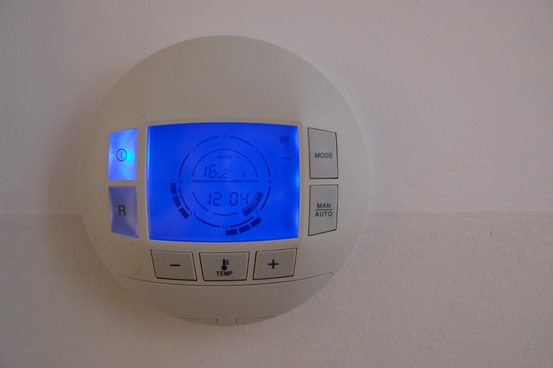 How to Set Your Programmable Thermostat. Photo of a digital thermostat mounted on a wall.